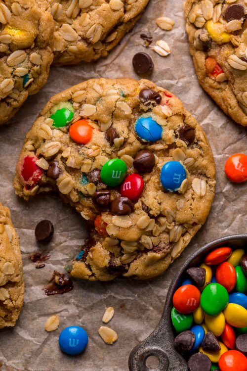 Monster cookies on baking sheet with a bite taken out.