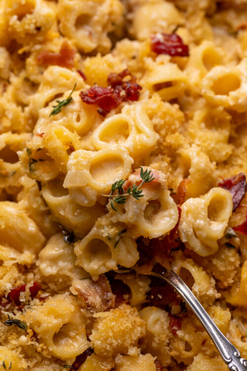 Baking dish with macaroni and cheese topped with bacon and thyme.